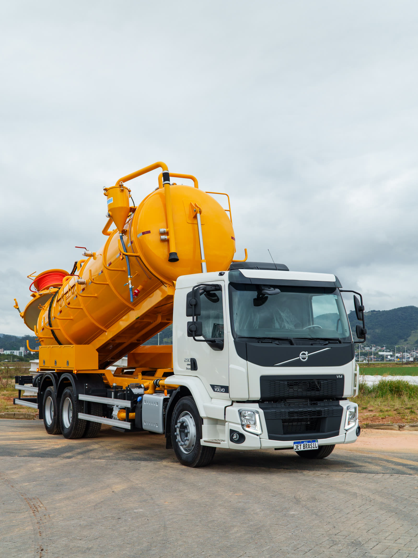 Tanque laranja montado em caminhão Volvo branco, basculado em ângulo alto