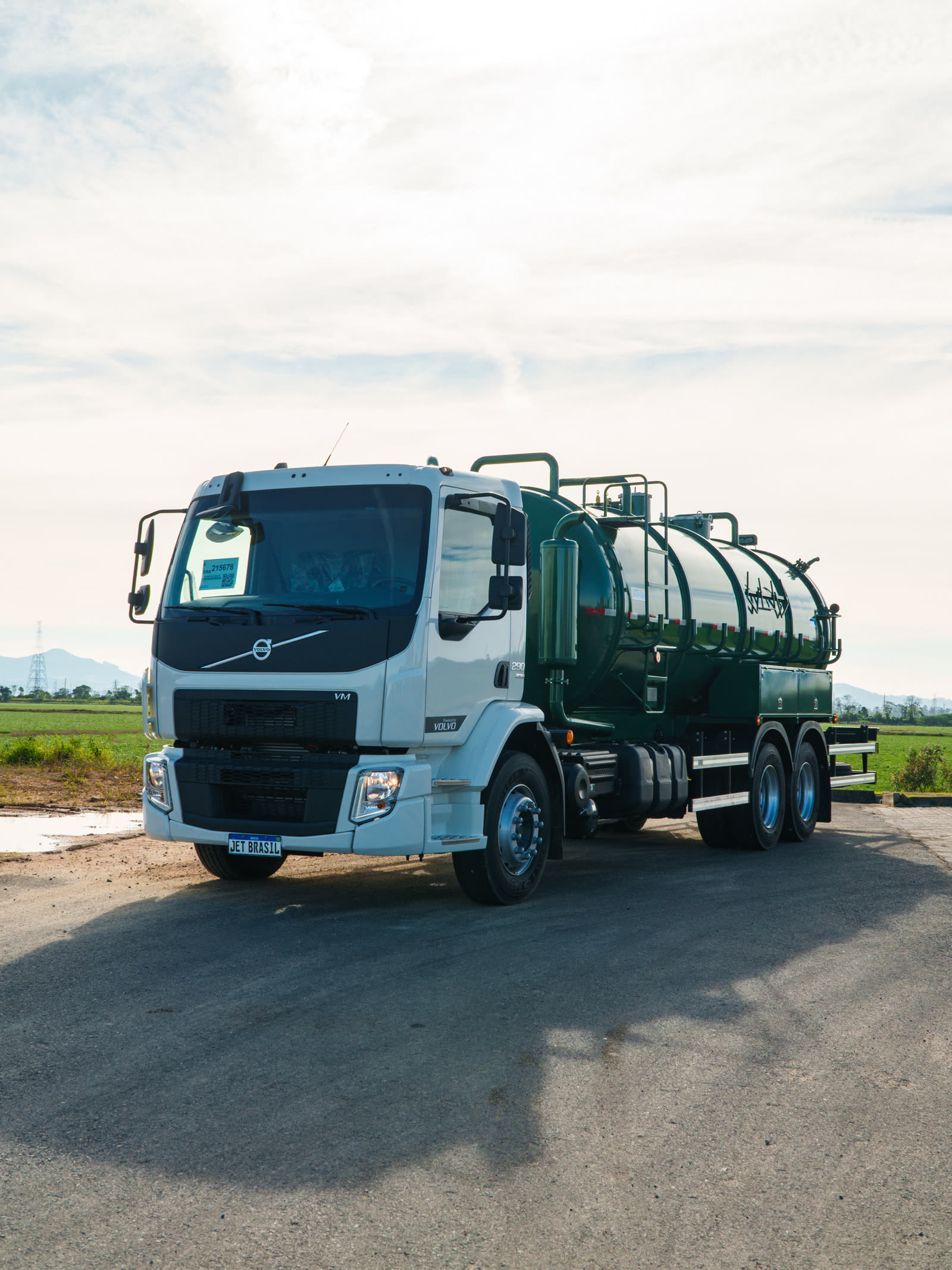 Caminhão Volvo branco com tanque de vácuo verde escuro, vista frontal